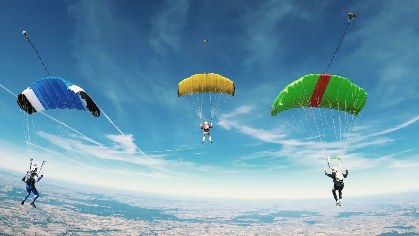 Colourful paraglider canopies drifting high above the landscape