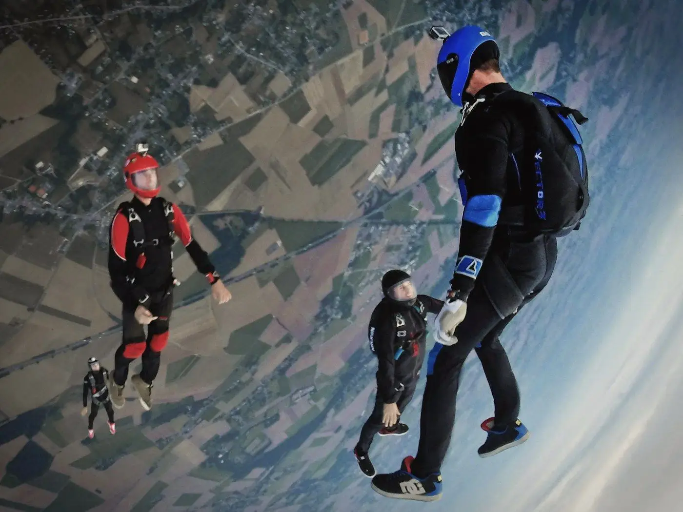 Skydivers in free fall high above a patchwork of fields