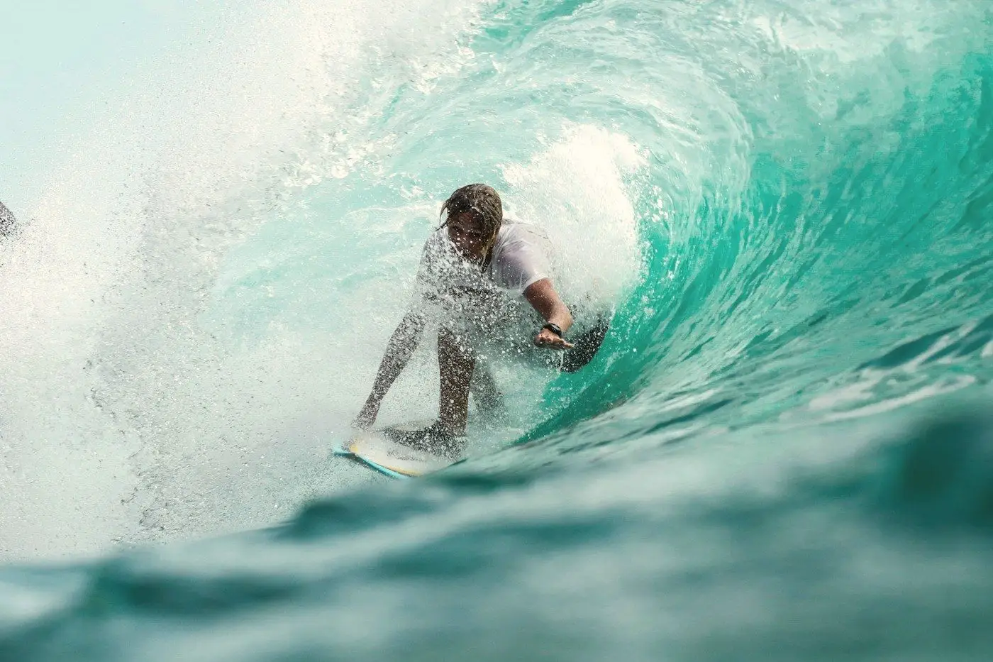 A surfer riding inside the curl of a translucent green wave