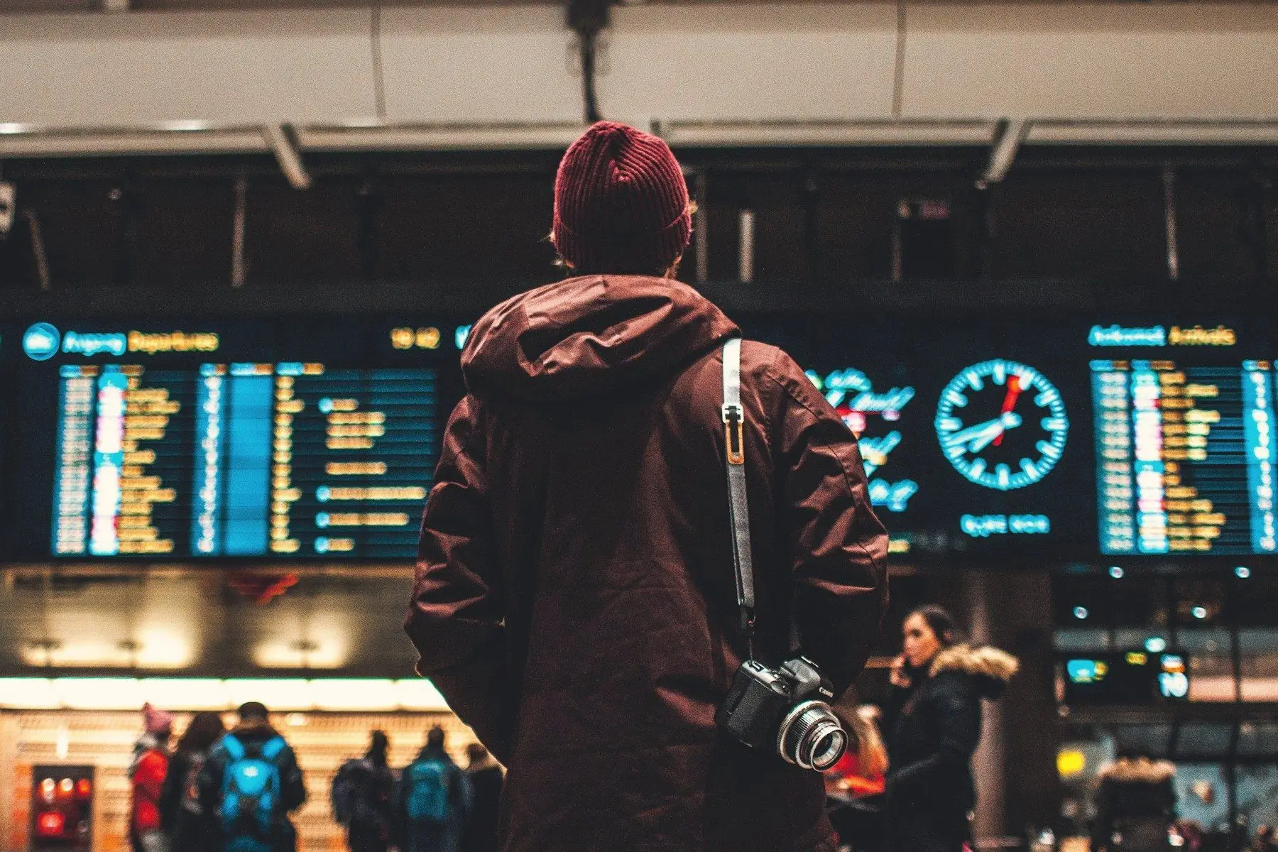 A traveller with a camera reading the departures board in a busy airport