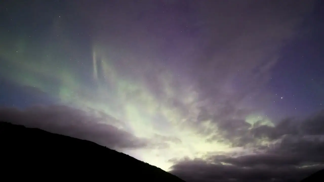 Northern lights over dark mountains at night