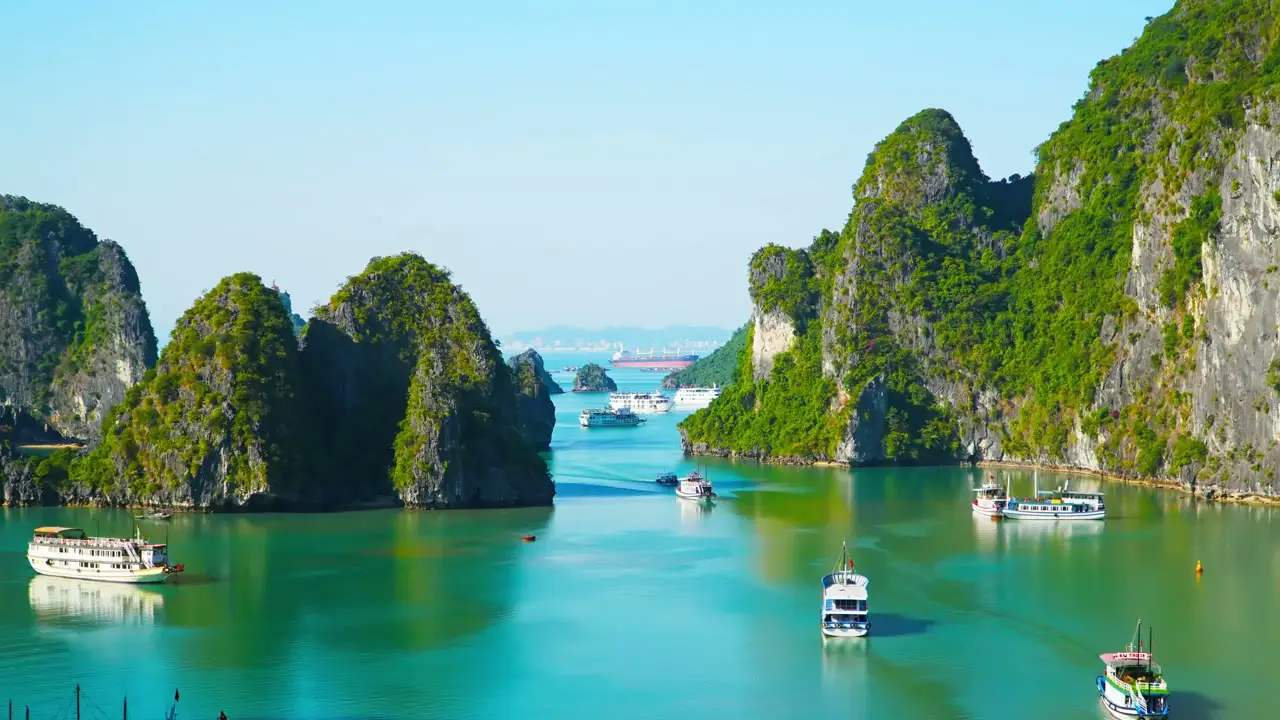 Boats crossing Ha Long Bay between steep, forested limestone islands