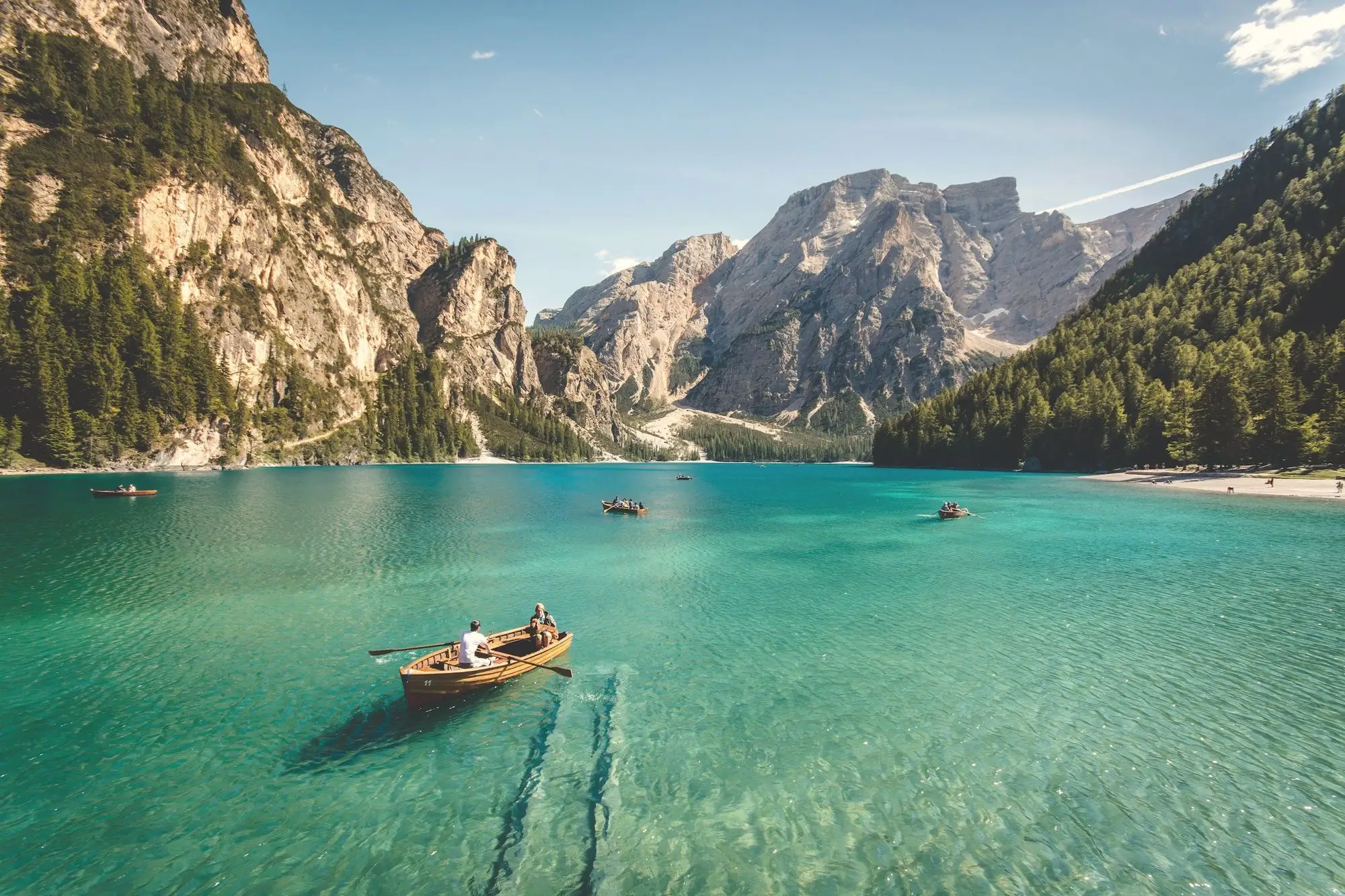 A rowing boat on a turquoise alpine lake beneath pale limestone peaks