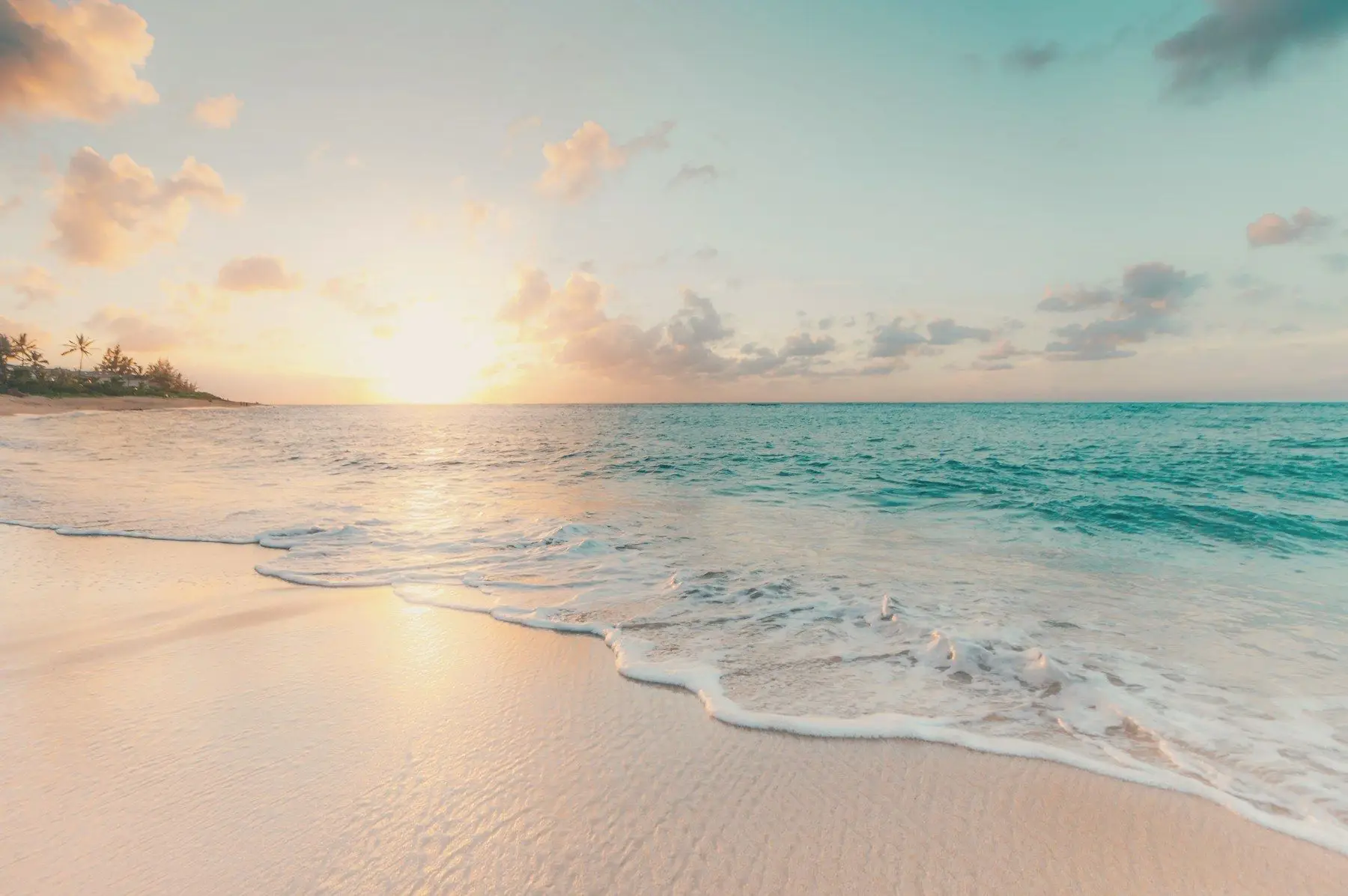 Gentle surf washing onto a pale beach at sunrise