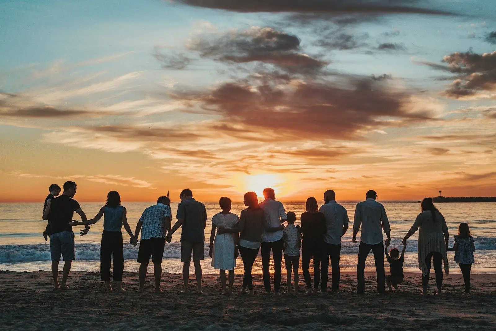 A family holding hands along the shoreline at sunset