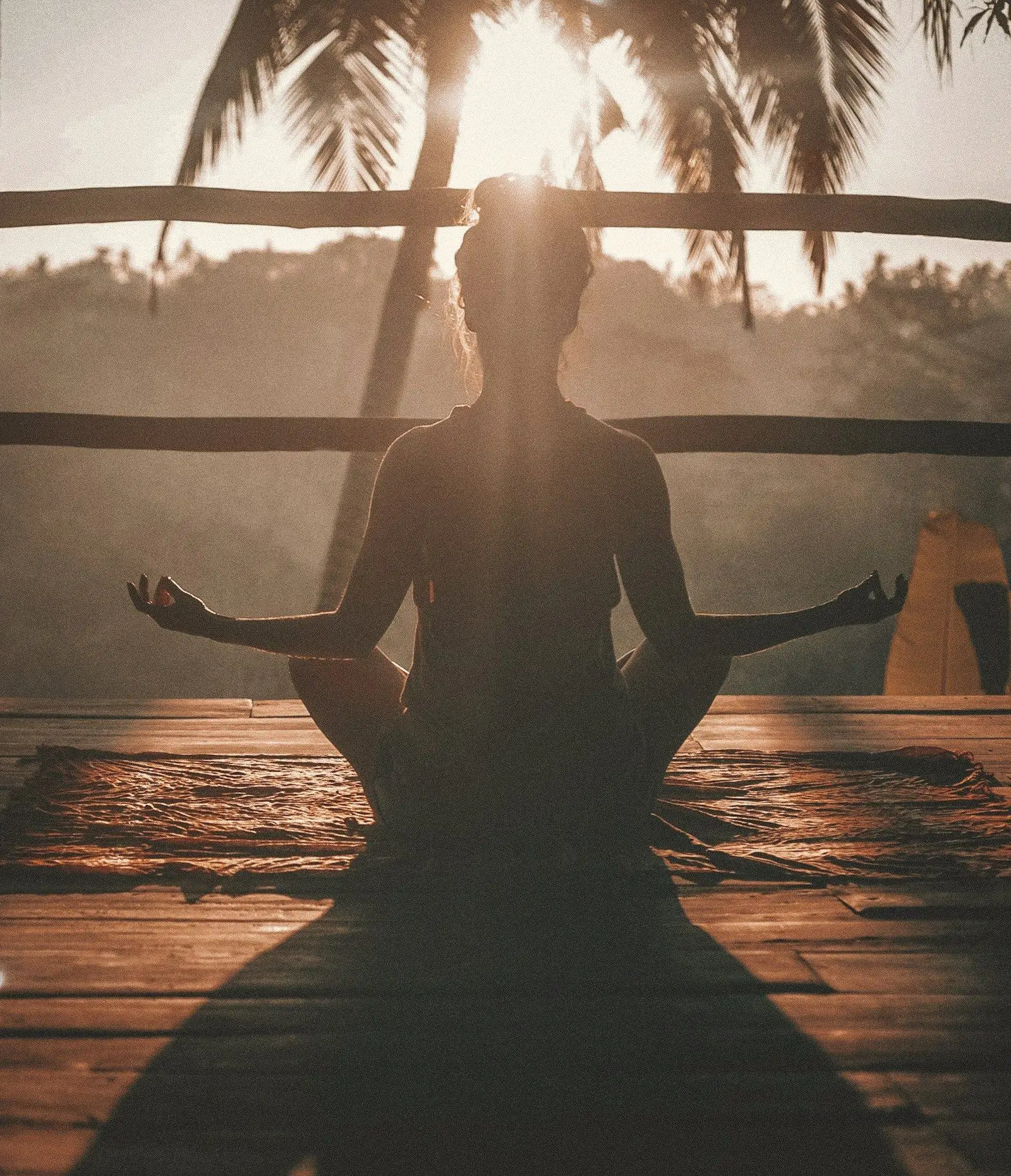 A person meditating in warm evening light on a wooden deck