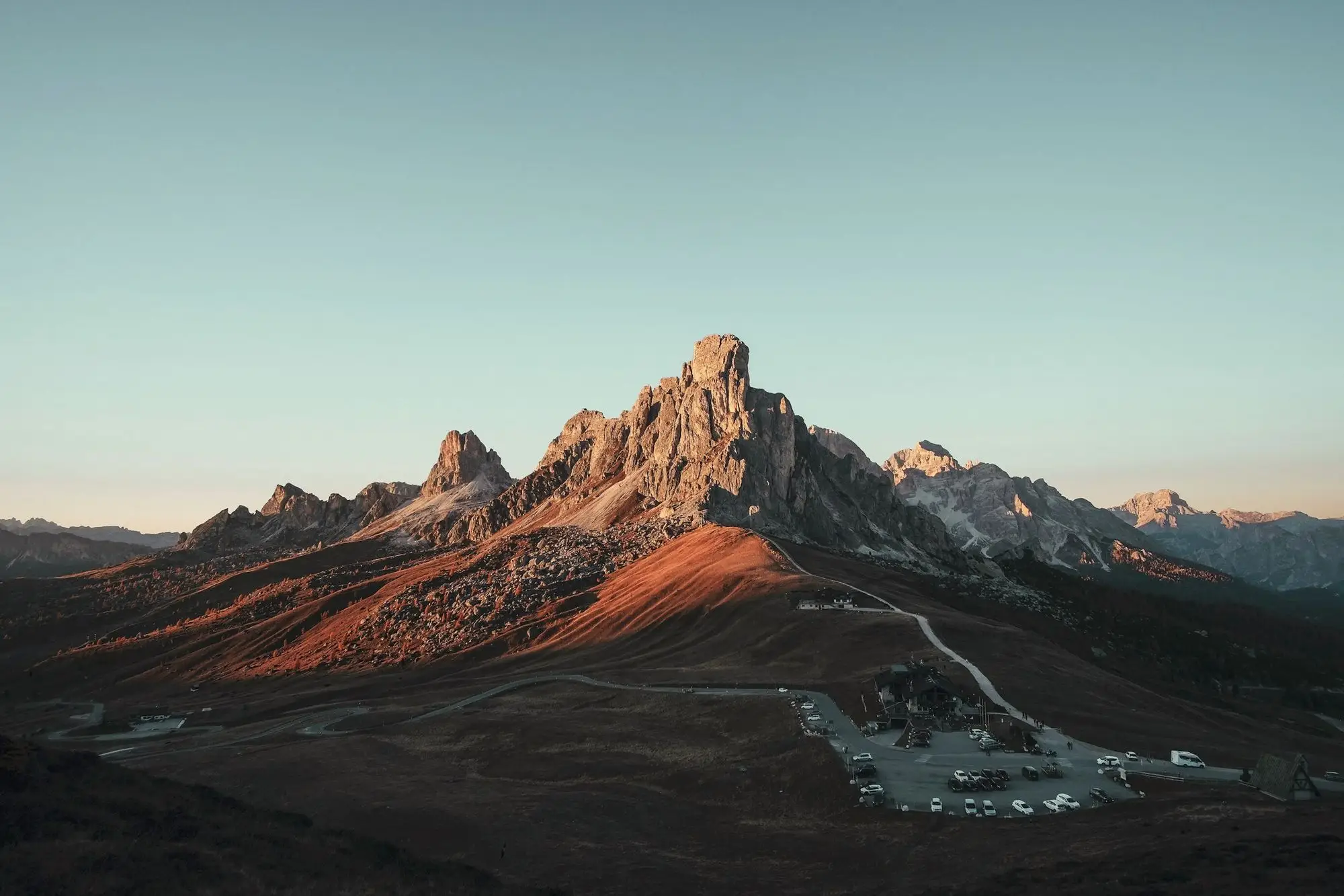 Alpenglow on jagged mountain peaks above a quiet valley at dusk