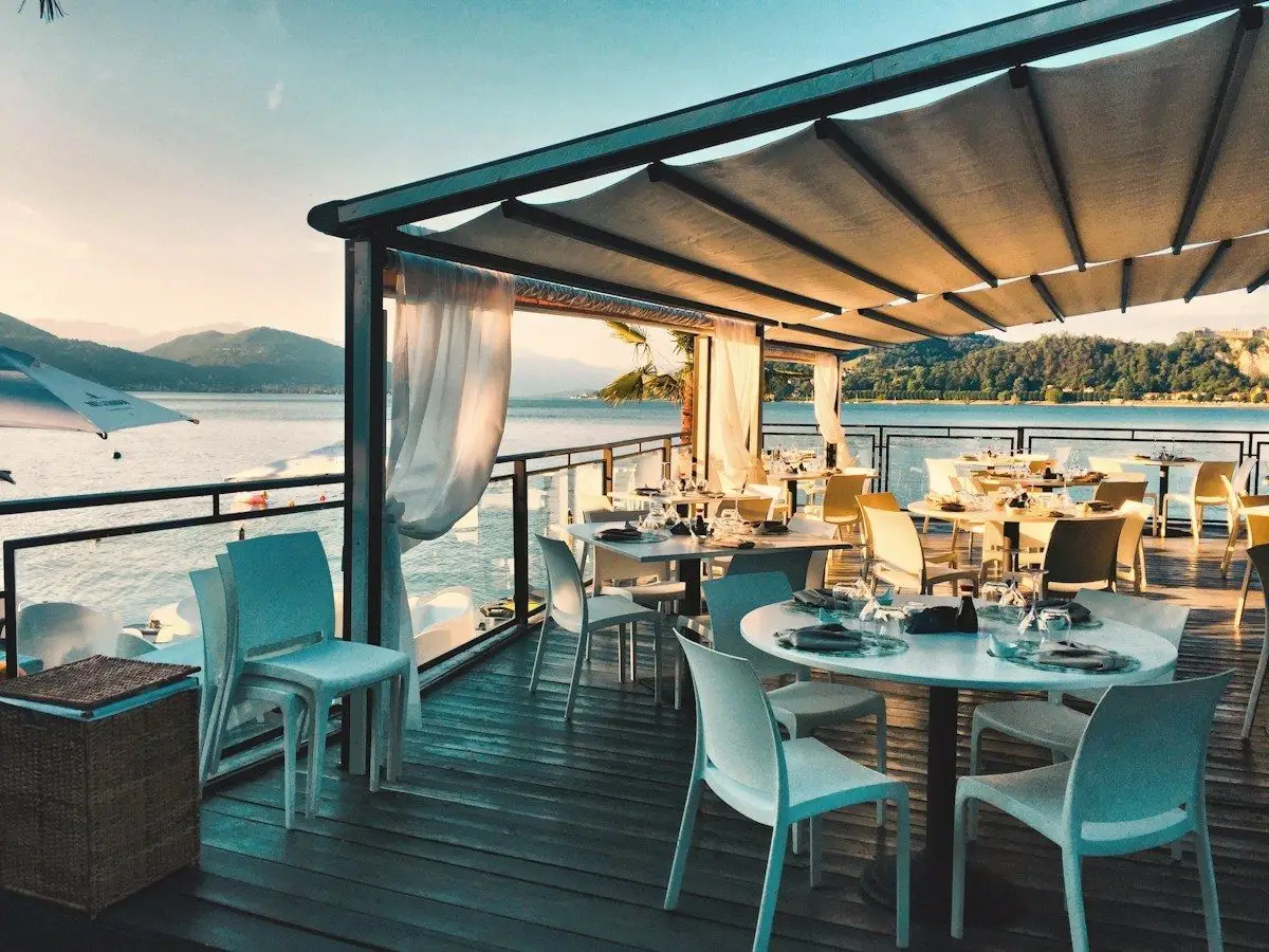 A shaded seaside dining terrace set for lunch above the water