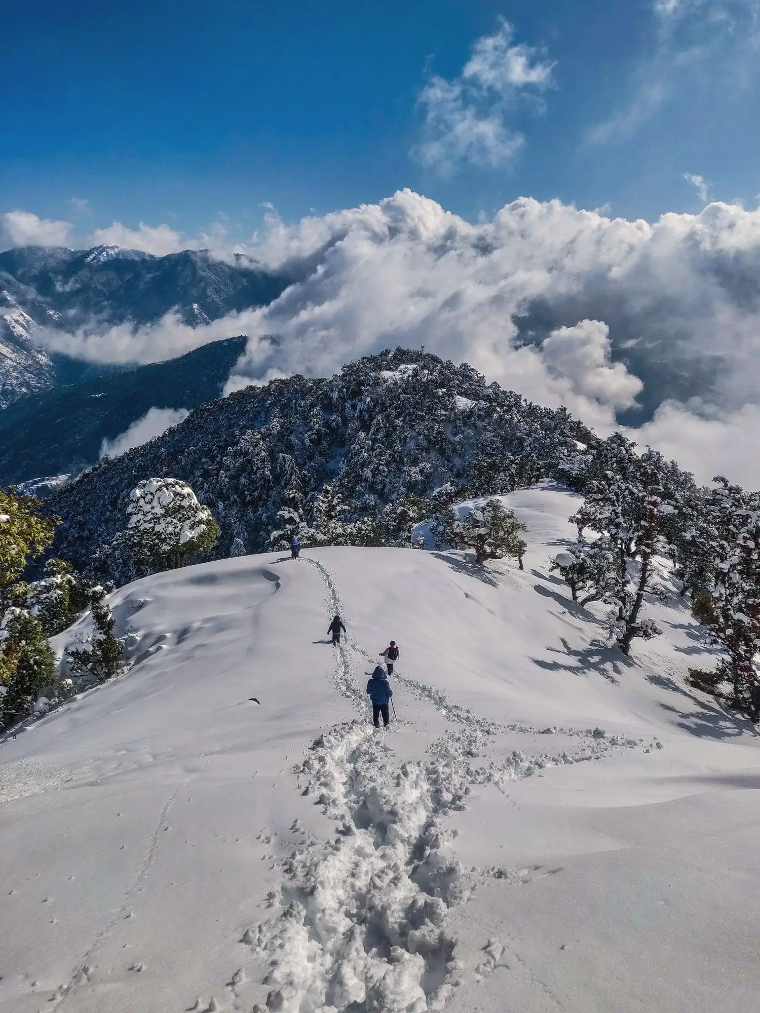 A trekker crossing a snowy Himalayan ridge above Manali