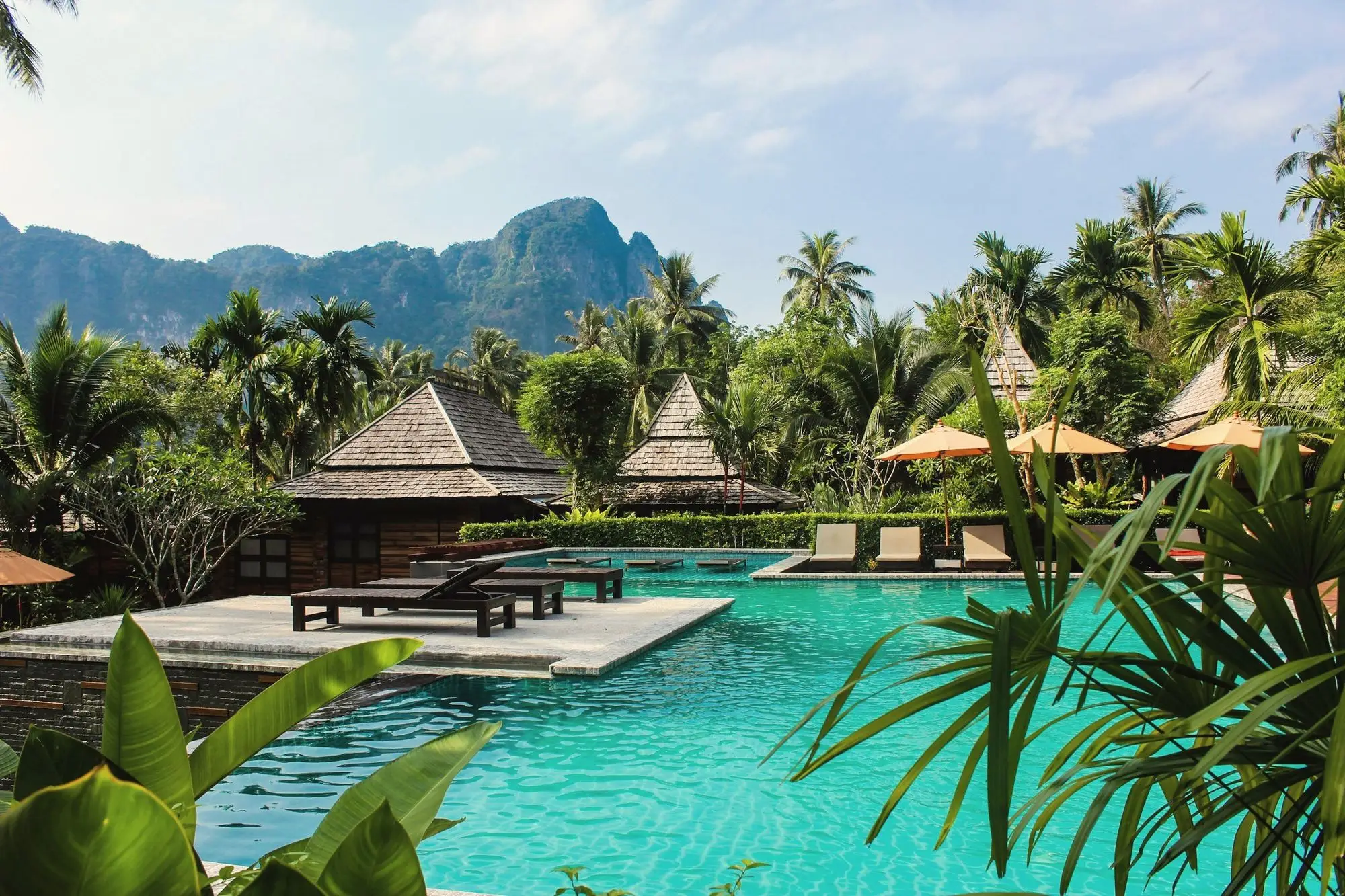 Illustrative image: a resort pool surrounded by tropical gardens and limestone hills