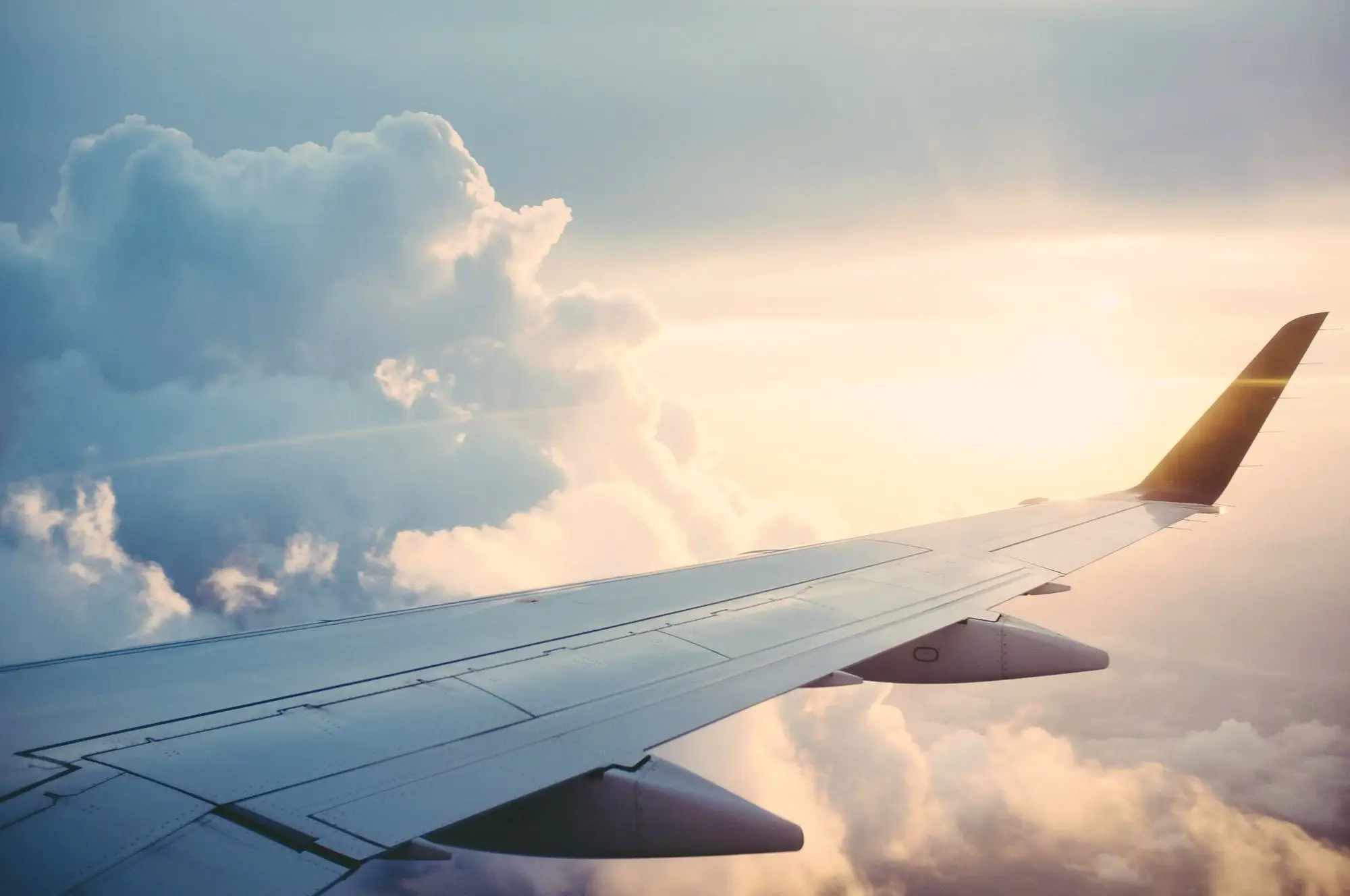 An aircraft wing above a sea of golden clouds at sunrise